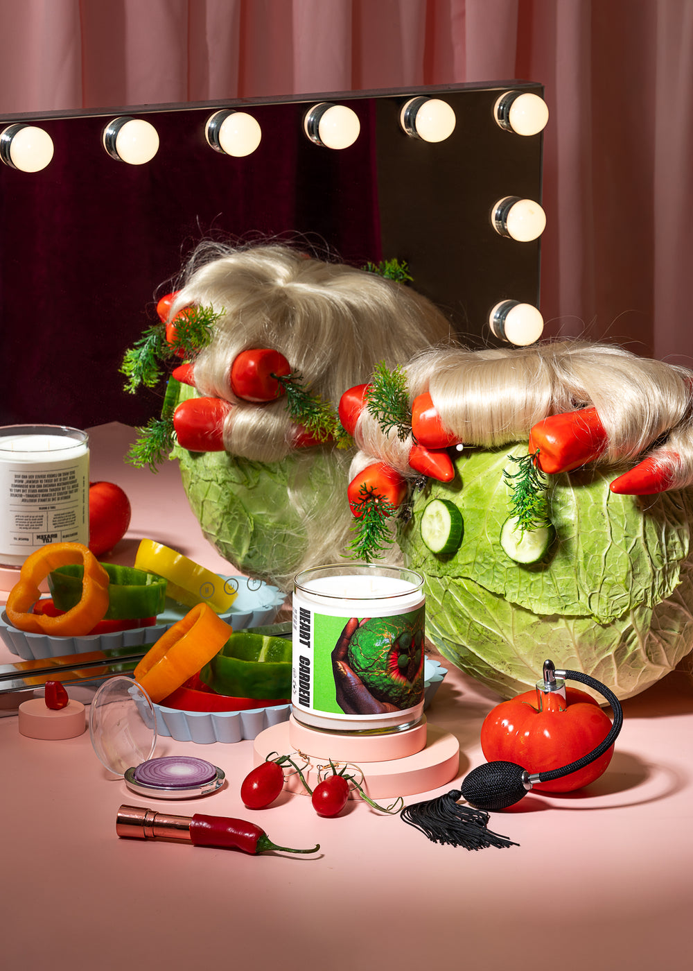 Makeup mirror with lights, wig, and various makeup items on a pink surface.