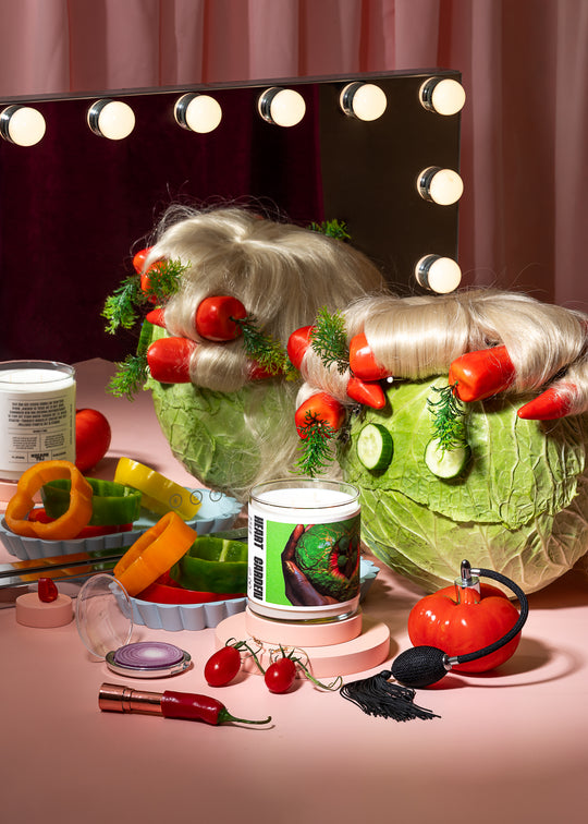 Makeup mirror with lights, wig, and various makeup items on a pink surface.